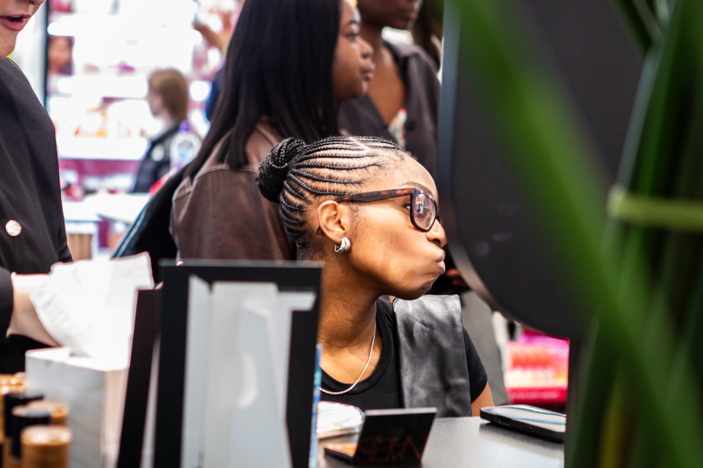 A guest in glasses leaning in to check her shade in the mirror at the Armani Beauty Luminous Silk Foundation masterclass