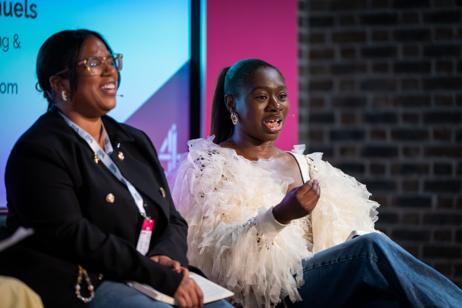 Tobi Oredein mid-sentence on the IPA panel, wearing a cream ruffled top